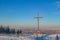 A huge wooden cross on top of Schoeckl, Austrian Alps during the morning golden hour. The peak is covered with powder snow.