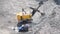 Huge yellow excavator loading stones into a truck