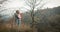 Hugging couple in love stands on a hillside looking down, young man and a woman admire the autumn forest growing on the