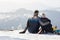 Hugging couple sitting on snow and enjoying in landscape