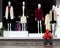 In Huizhou Commercial Pedestrian Street, a man is playing mobile phone and smoking in front of a clothing store window.