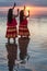 Hula dancers in ocean at sunset