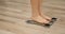 Human barefoot steps on body weight scales. Woman checking weight on scale in room. Girl measuring overweight