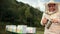 Human beekeeper in special clothes, holding a smoker to calm the bees