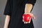 Human in a black T-shirt stretched out his hand, holding the red plastic heart out the front.Selective focus