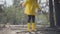 Human body in yellow rubber boots and coat balancing in the tree trunk