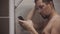 Human with cell phone in shower, washing head