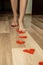 Human female feet walk along road of red valentine hearts. laid out on wooden floor of house. Surprise. Relationship