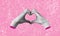 Human female hands, depicting a heart shape, on a pink background. Feelings and emotions