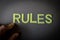 Human finger pointing the word Rules written with plastic letters on dark gray paper background