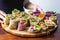 human fingers arranging colorful vegan wraps on a wooden tray