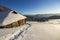 Human footprint path in white deep snow leading to small old wooden forsaken shepherd hut in mountain valley, spruce forest, woody