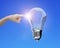 Human forefinger touching lightbulb with wind turbines inside