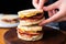 human hand adding bacon slice to an english muffin sandwich