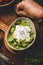 Human hand adding black sesame to fresh green purslane salad