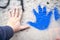 Human hand and bright blue palm print with paint spots on the external wall surface. Plastered texture, grey background. Copy