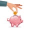 Human hand depositing coin in a money piggy bank
