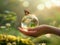 Human hand gently holds a transparent globe with a butterfly sitting on it. Visual metaphor for environmental awareness and