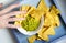 Human hand grab nachos corn chips with guacamole sauce close up photo