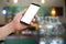 Human hand hold smart phone, tablet, cellphone with white blank screen on blurry coffee shop Background.