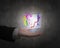 Human hand holding glowing colorful transparent glass cube