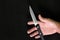 Human hand holding a knife in dark black background. Murder, killer and suicide concept.