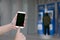 Human hand holding mobile smart phone  with Automatic Teller Machine blur background