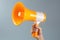 Human hand holding orange megaphone