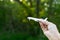 Human hand holding white airplane model front a green tree background. Air transportation trip concept