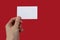 Human hand holds a blank sheet of paper on a red background with blank space for text