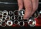 Human hand holds a chrome socket head from a interchangeable socket set. Manual tools in auto repair shop, close up