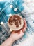 Human hand holds a cup of coffee on a blue plaid in the garland lights top view