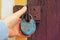 A human hand holds an old vintage lock against the background of an old wooden door.