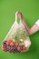 Human hand holds string bag mesh with vegetables and fruits. Zero waste shopping concept.