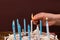 Human hand with matchstick, lighting a candle on a birthday cake