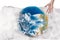 Human hand near the globe which is all in plastic, our irresponsible, excessive consumption of plastic
