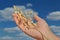 Human hand with oat spikelet against deep blue sky