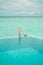 Human hand over water shot behind the edge of swimmig pool on background of Indian coean