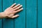 human hand palm on vertical green wooden planks with peeling paint, texture close-up