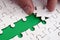 The human hand paves the way to the surface of the jigsaw puzzle, forming a green space. The concept of overcoming the difficultie