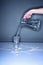 Human hand pouring water into an overflowing glass. Conceptual image