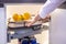 Human hand pushes the pull-out shelf with fresh lemons in the contemporary modern convenient kitchen cupboard