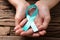 Human Hand Showing Teal Ribbon To Support Breast Cancer Cause