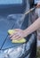 Human hand with sponge soap washing car.