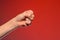 Human hand that squeezed fingers into a fist, symbolizing hatred and resistance, isolated on a red background