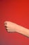 Human hand that squeezed fingers into a fist, symbolizing hatred and resistance, isolated on a red background