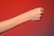 Human hand that squeezed fingers into a fist, symbolizing hatred and resistance, isolated on a red background