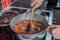 Human hand stirring a saucepan of vegetables with a wooden spoon whilst making soup