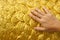 Human hand touching golden cement plaster in fish skin curve pattern wall background.