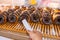 Human hand using clamp picking frosted chocolate donut at bakery